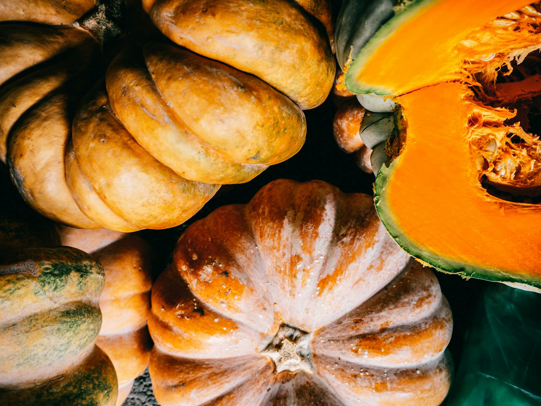 ripe organic pumpkins heaped on plastic surface