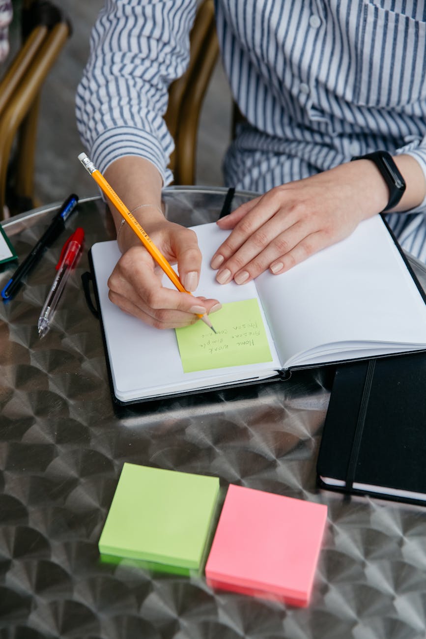 making a note in pencil on a sticky note in the planner