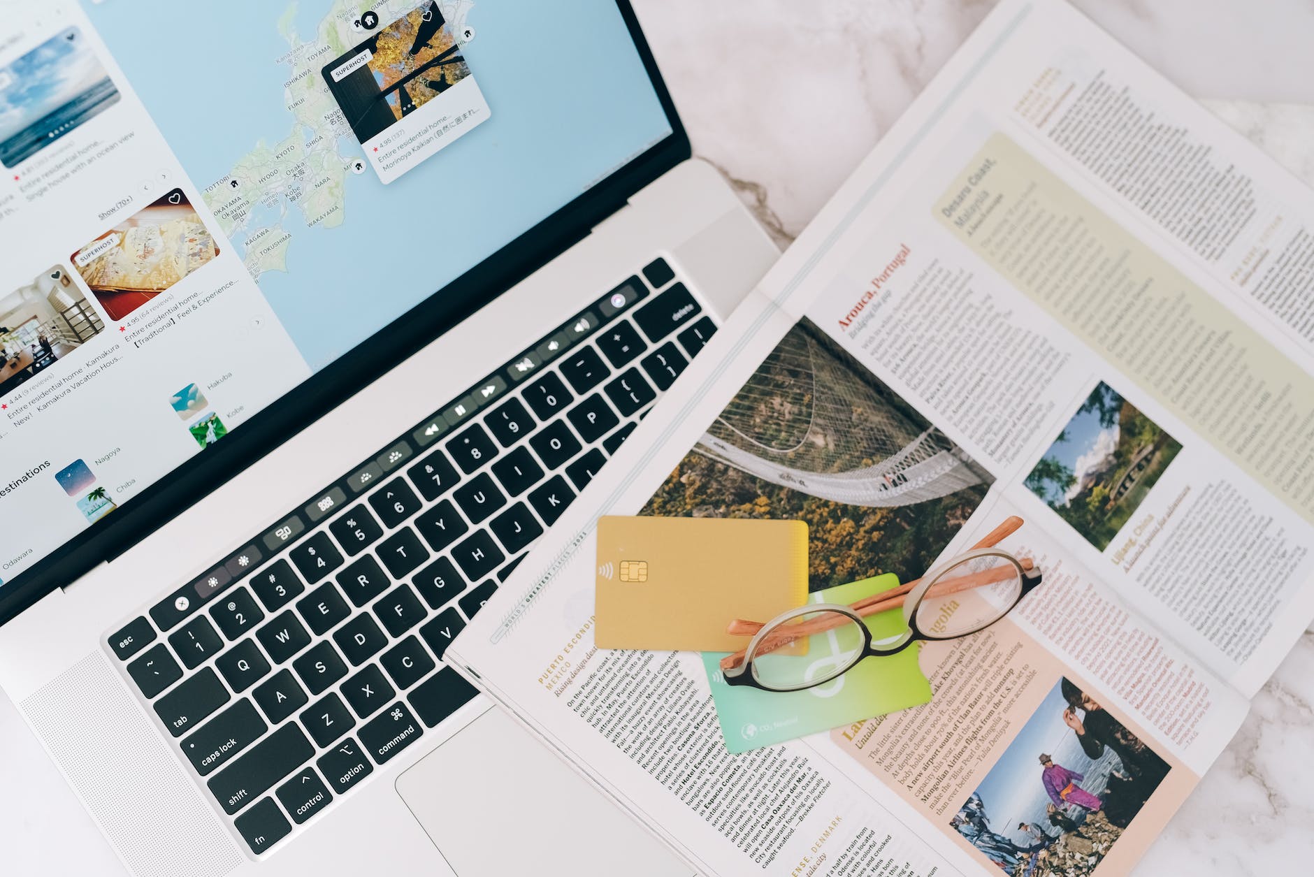 magazine credit cards a laptop and eyeglasses on a table